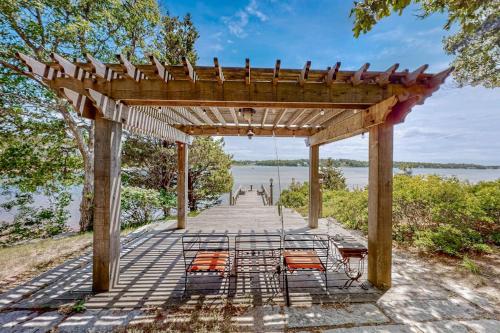 a wooden pergola with chairs and a view of the water at Capeview Estate in Bourne