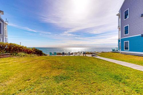 a house with a lawn next to the ocean at Summer Cape Escape in Dennis Port