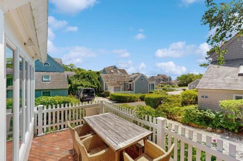a patio with a wooden table and chairs on a white fence at Shoreline Escape in Mashpee