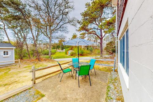 a patio with a table and chairs and an umbrella at Nauset Beach Getaway in Orleans