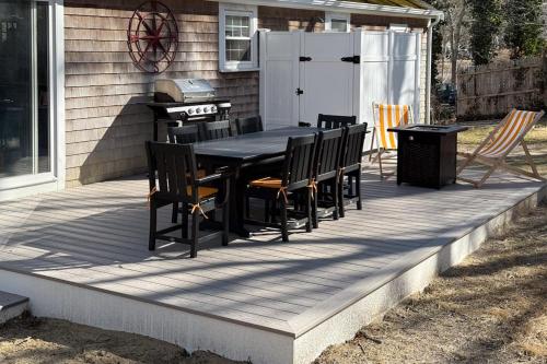 a wooden deck with a table and chairs on it at Champagne Dreams in Dennis