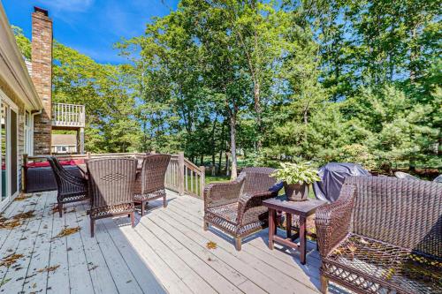 a deck with wicker chairs and a wooden table at Sanctuary In The Woods in East Falmouth