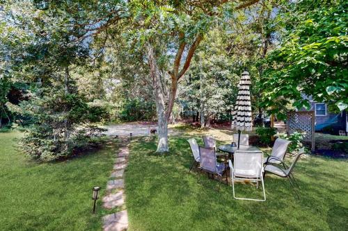 a table and chairs in a yard with a tree at Oak Leaf Cape Cottage in Oak Bluffs