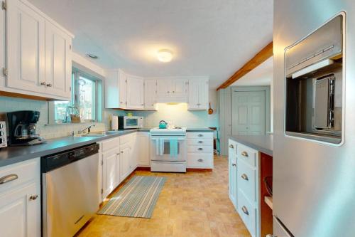 a large white kitchen with white cabinets and appliances at Salty Ridge Station in Orleans