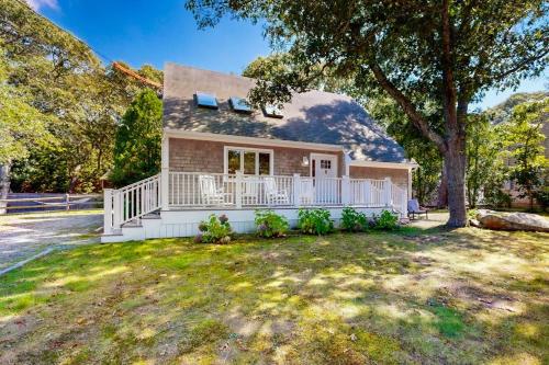 a small house with a white porch and a tree at Set Sail in Oak Bluffs