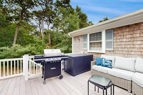 a barbecue on a patio with a couch and a couch at Seabreeze in Dennis Port
