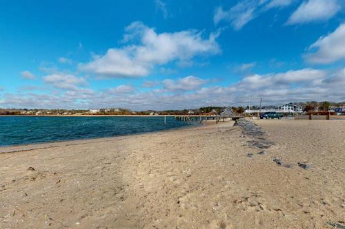 a sandy beach with a pier in the water at Megansett Glen in North Falmouth