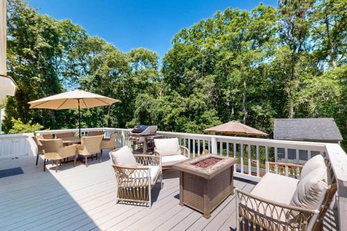a deck with chairs and tables and an umbrella at Megansett Glen in North Falmouth
