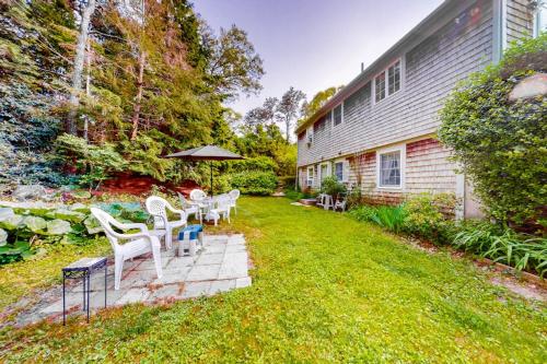 ein Garten mit weißen Stühlen und einem Sonnenschirm in der Unterkunft Haven Cottage in Brewster