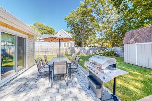 a patio with a table and a grill and chairs at Falmouth Beach House in Falmouth