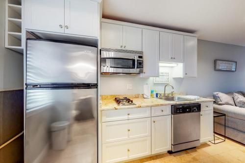 a kitchen with white cabinets and a stainless steel refrigerator at Immaculate Beach Condo in Dennis Port