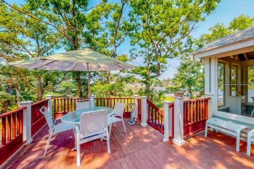 a deck with a table and chairs and an umbrella at Cottage by the Bay in Pocasset