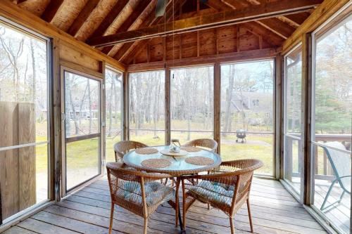 a dining room with a table and chairs on a porch at The Tranquil Heron Cottage in Eastham