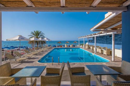 una piscina con mesas y sillas y el océano en Stalis Hotel, en Stalida