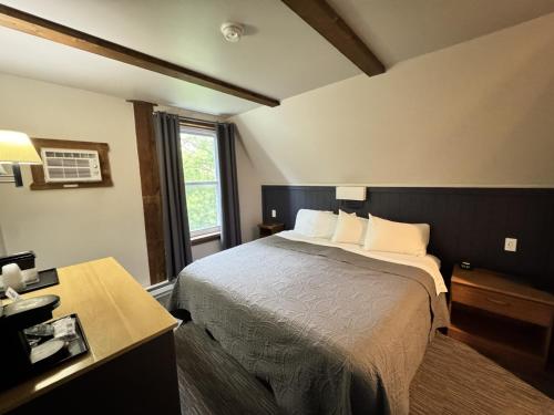 a bedroom with a bed and a desk and a window at Lake Ontario Motel & Inn in Newfane