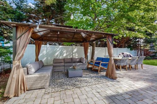 a pergola with couches and a table and chairs at Strawberry Hill Haven in Hyannis