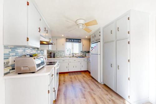 a kitchen with white cabinets and a ceiling fan at Swift Beach House in Wareham