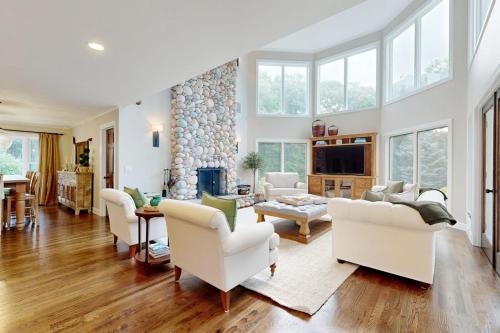 a living room with white furniture and a stone fireplace at Bird's Paradise in Oak Bluffs