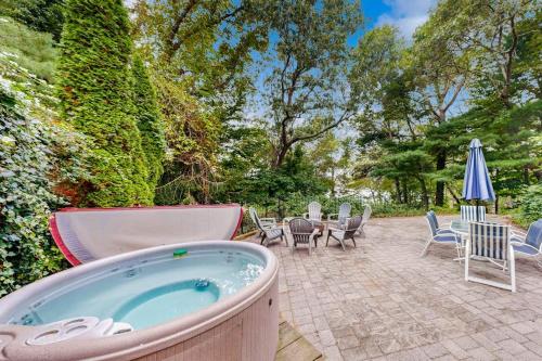 a hot tub on a patio with chairs and an umbrella at Mermaid's Rest in Centerville