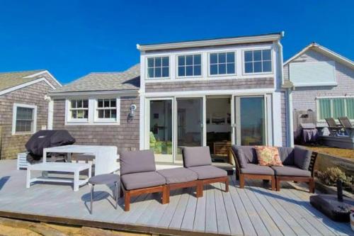 a deck with chairs and a table and a house at Seas The Day in North Truro