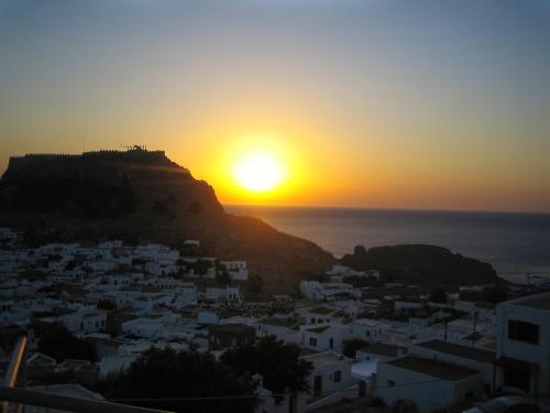 a view of the sun setting over a city at Lindos Panorama in Líndos