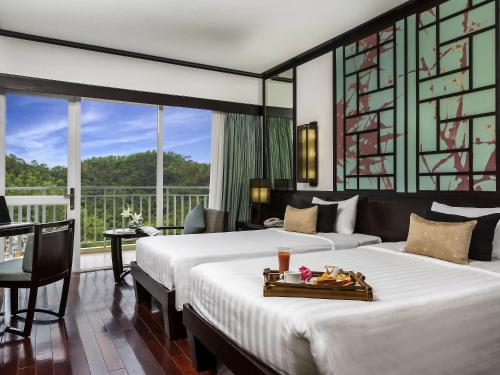 a hotel room with two beds and a balcony at Novotel Ha Long Bay Hotel in Ha Long