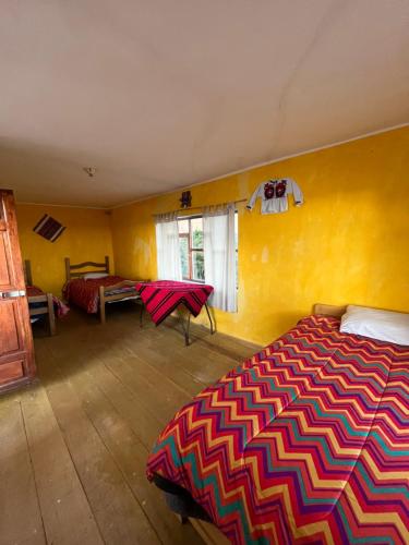 a bedroom with a bed and a yellow wall at Qocha Simi Homestay in Ocosuyo