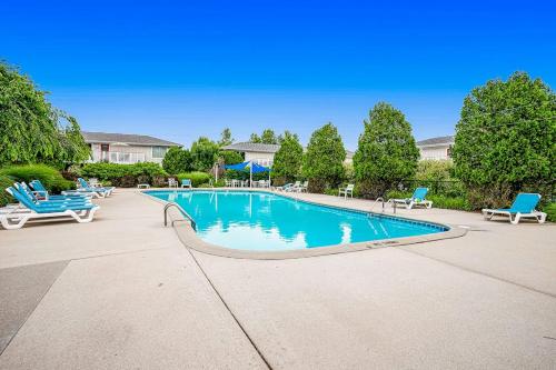 a large swimming pool with blue chairs and trees at Bluebird Condo in Douglas