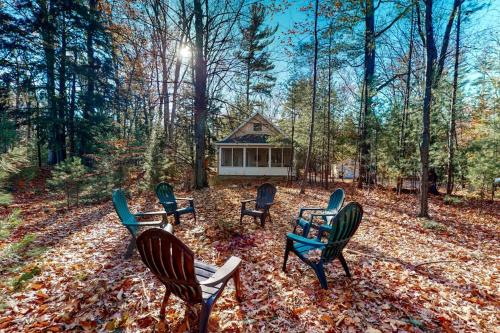 a group of chairs and a cabin in the woods at Uncle Warren's Retreat in Glen Arbor