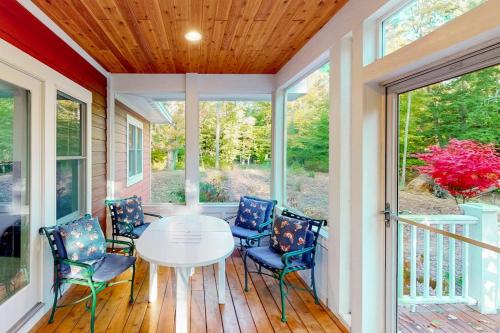 a screened porch with a white table and chairs at Cardinal Corner in Glen Arbor