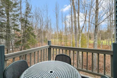 a table and chairs on a porch with a view of the woods at Wintergreen Condo, Unit #543 in Thompsonville