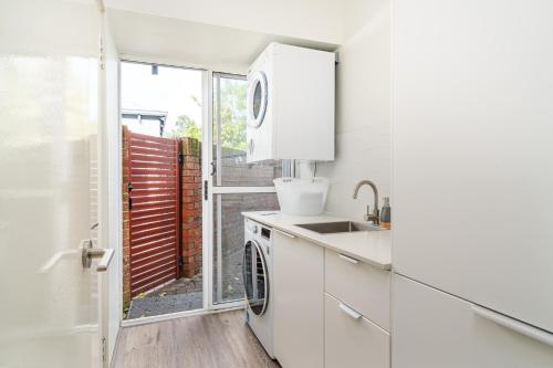 a white kitchen with a sink and a dishwasher at Abby’s Beach Villa in Broadwater