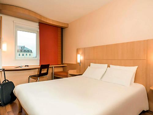 a bedroom with a large white bed and a desk at Hôtel Ibis Vitré Centre Ville climatisé in Vitré