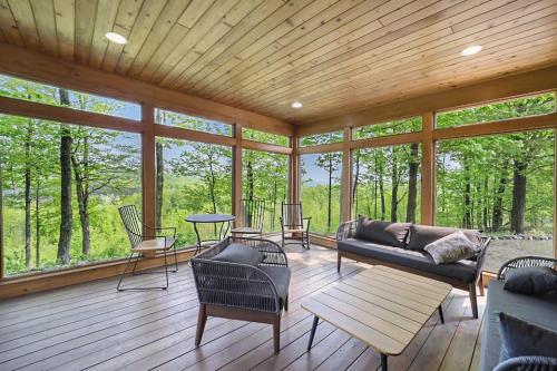 a screened in porch with a couch and chairs at Sorellina House in Maple City