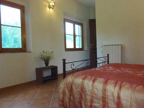 ein Schlafzimmer mit einem Bett und zwei Fenstern in der Unterkunft Podere Mazzana in Marti
