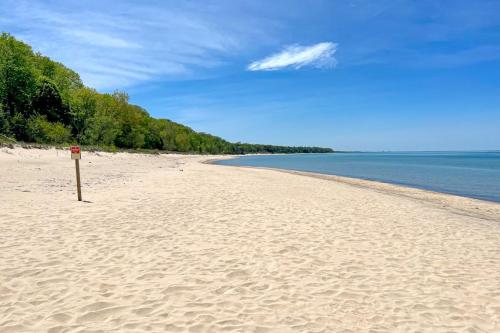 a beach with a sign in the sand and water at The Gatehouse on Orchard Beach in Lakeside