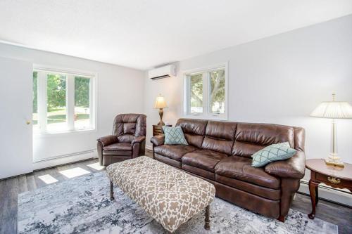 a living room with a leather couch and a chair at Harbor Charm in Harbor Springs