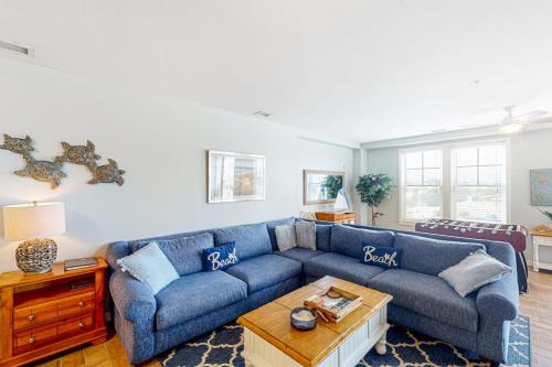 a living room with a blue couch and a table at The Sanctuary - Summer Breeze A114 in Virginia Beach