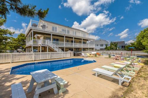 a large house with a swimming pool and lounge chairs at Down By The Sea in Virginia Beach