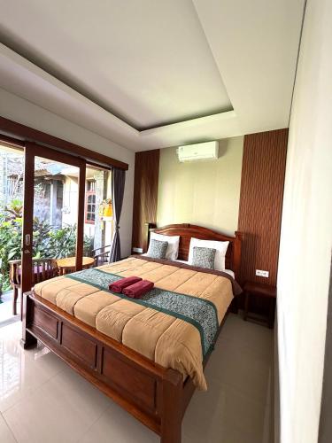 a bedroom with a bed and a large window at Kope House Ubud in Ubud