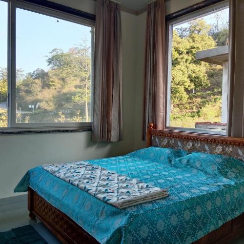 a bed in a bedroom with two windows at Thano Retreat in Dehradun