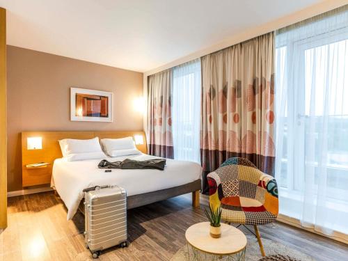 a hotel room with a bed and a chair at Novotel Edinburgh Park in Edinburgh