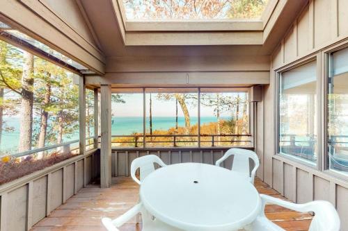 a white table and chairs on a porch with windows at Hawks Nest 58 in Glen Arbor