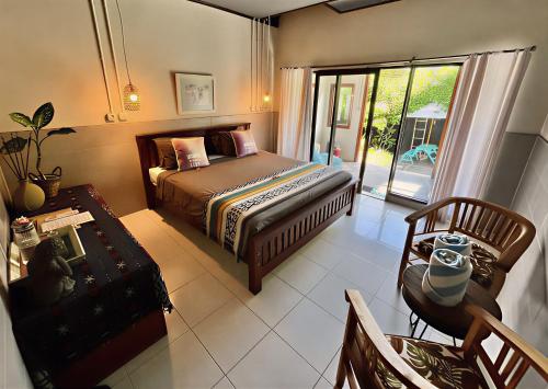 a bedroom with a bed and a chair and a window at Secret Garden Surf Resort, walk to waves in Pulau Gilkaliantan