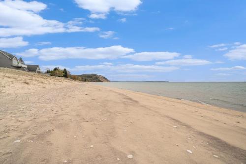 a sandy beach with a house and the ocean at Cedar Crest in Empire