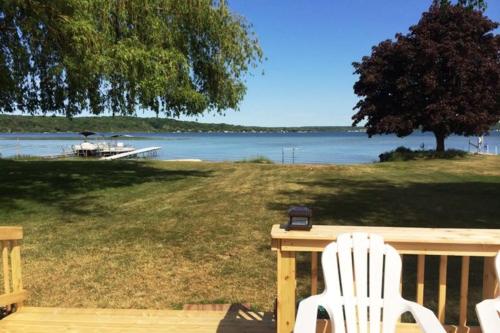 two white chairs sitting on a deck overlooking a lake at The Summer House in Onekama