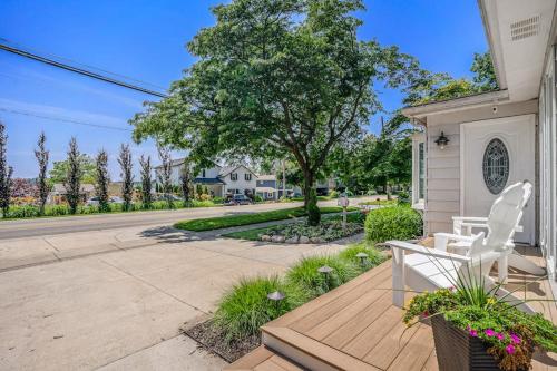 a white chair sitting on a wooden deck next to a house at Serenity Now in Saugatuck