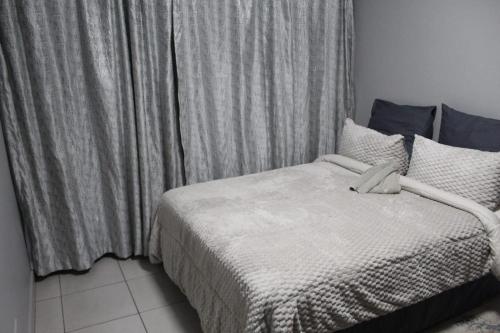a bedroom with a bed and a window with curtains at Penthouse in Bloemfontein