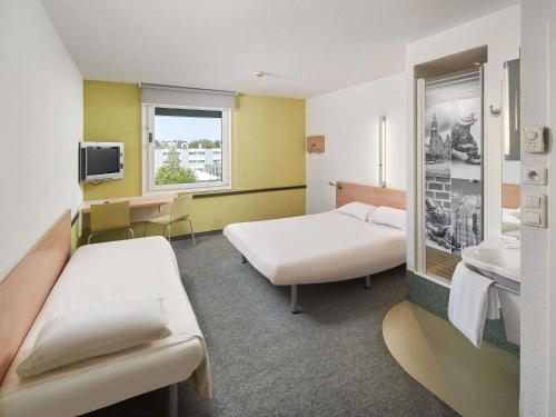 a hotel room with two beds and a tv at ibis budget Wrocław Południe in Wrocław
