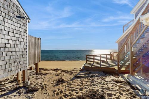 a wooden bench on the beach next to a building at Bayside Breeze in Truro